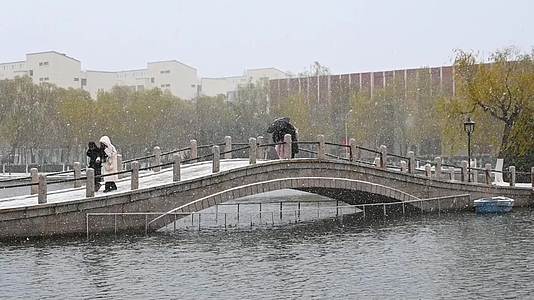 冬天大雪行人打伞走过石桥的慢镜头视频的预览图