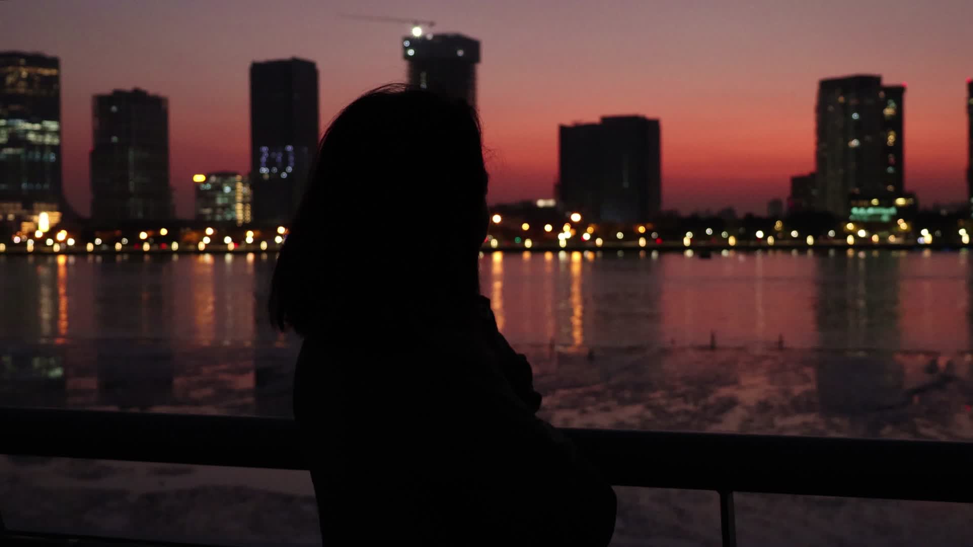 黄昏夜晚站在城市江边的东方女性背影视频的预览图