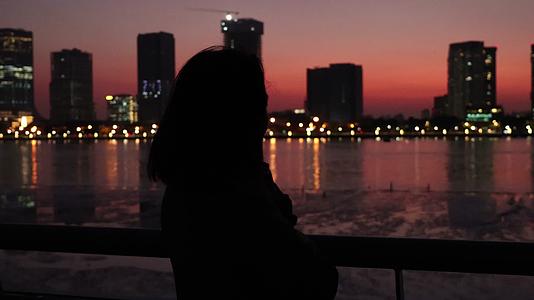 黄昏夜晚站在城市江边的东方女性背影视频的预览图