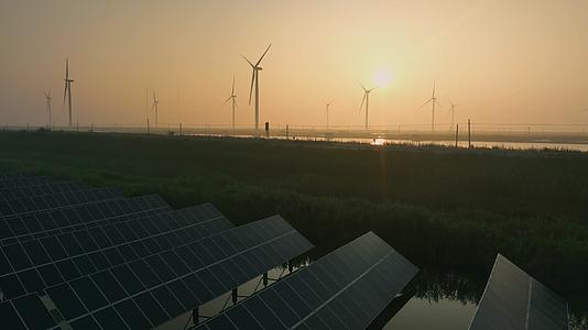 日出下的乡村里的太阳能光伏板和风力发电机视频的预览图