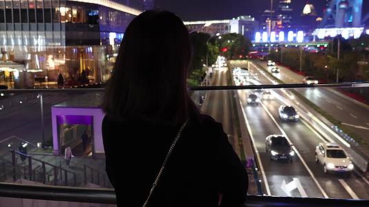 夜晚站在城市户外思考的女人背影视频的预览图