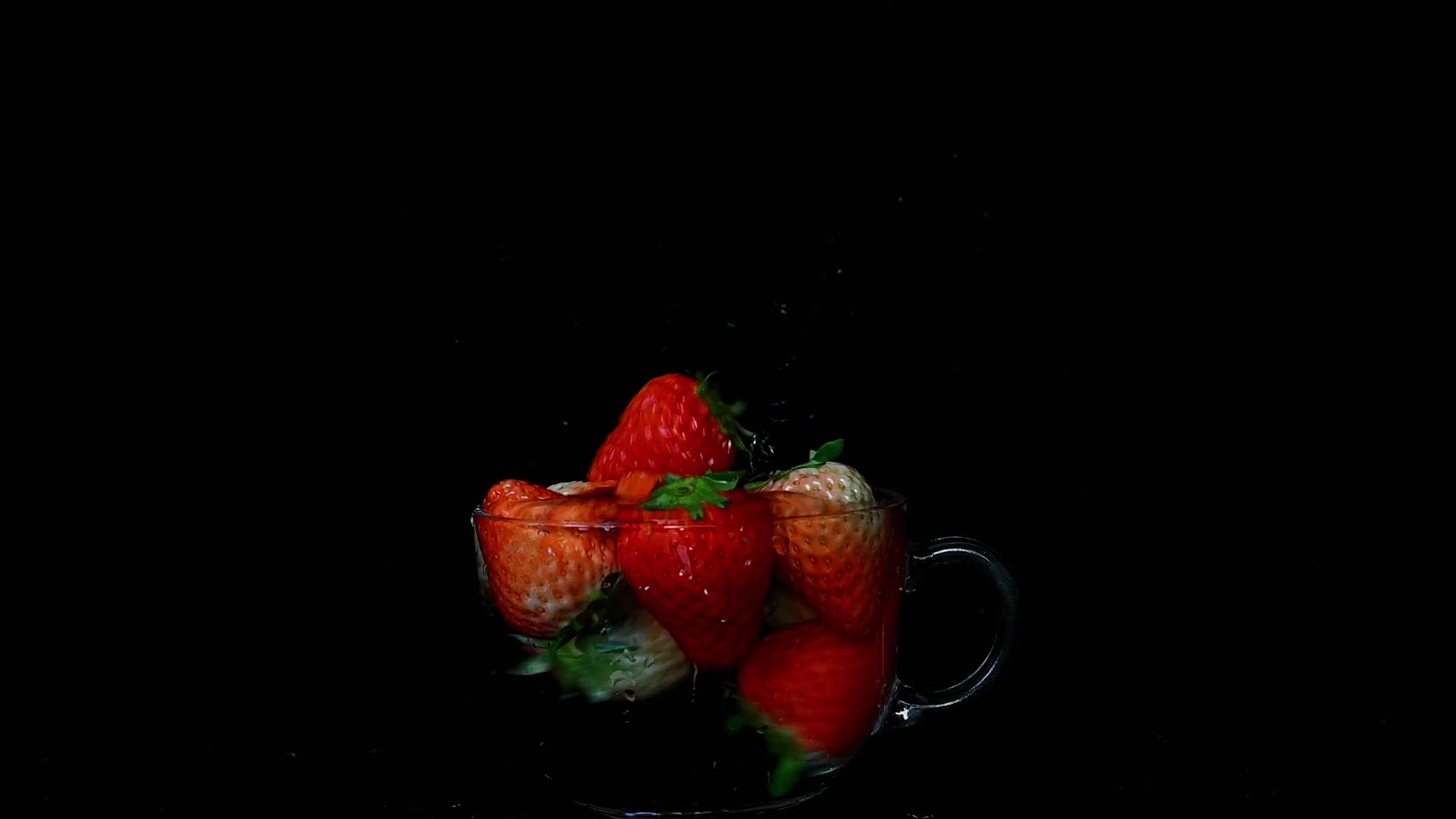 草莓落入玻璃杯中溅起水花的慢镜头视频的预览图