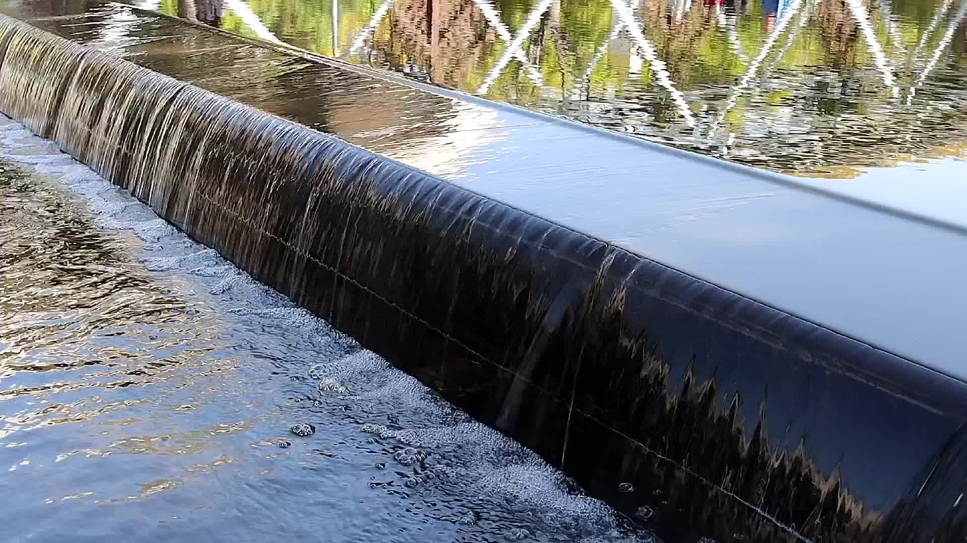 春日阳光公园溪水小瀑布和绿树倒影视频的预览图