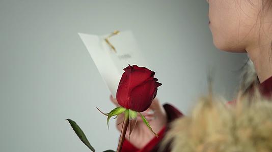 4K情人节美女拿着玫瑰花阅读卡片升格视频视频的预览图