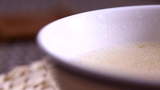 勺子盛起浓稠奶白大骨汤视频的预览图