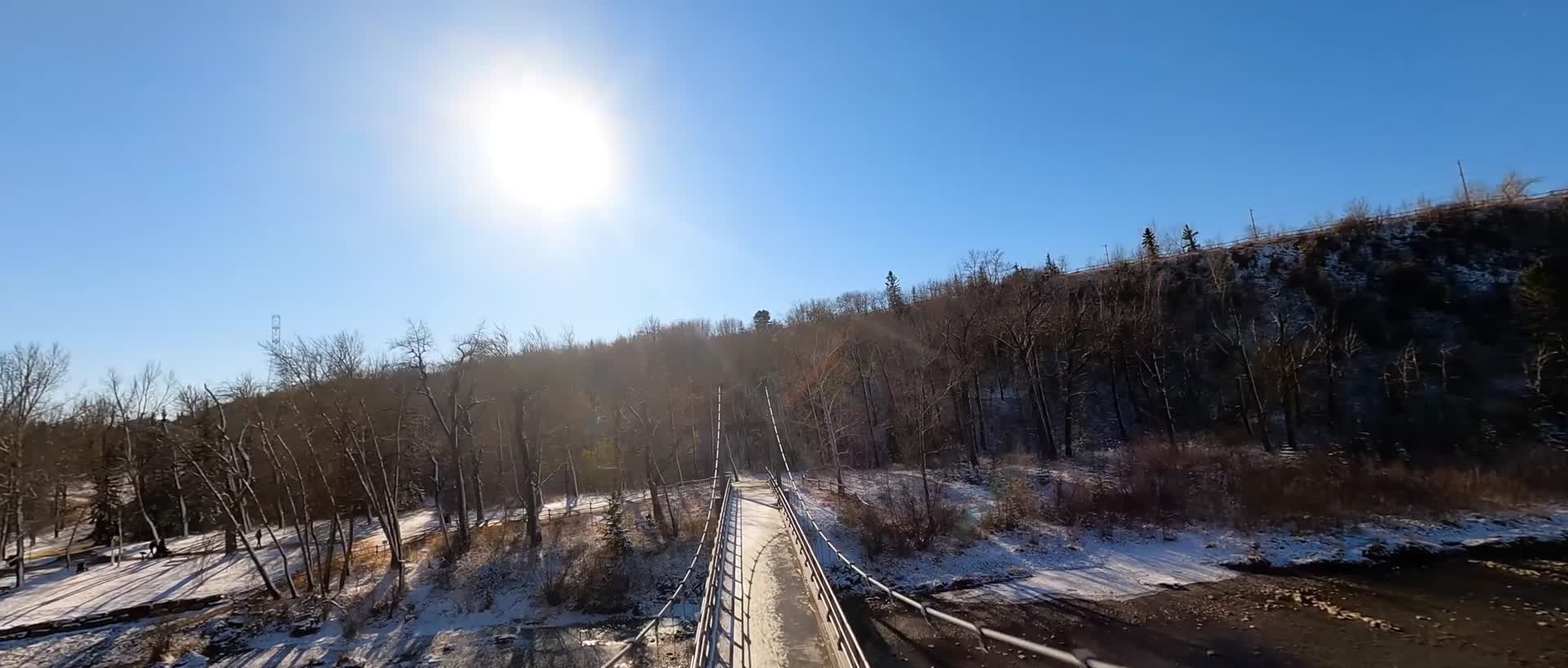 穿越机飞越吊桥河流冬季阳光视频的预览图