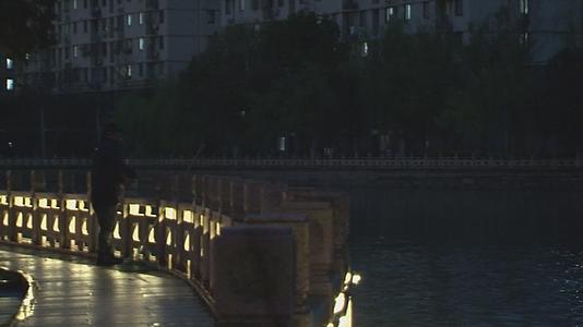 春雨夜幕下都市古镇桥边钓鱼人视频视频的预览图