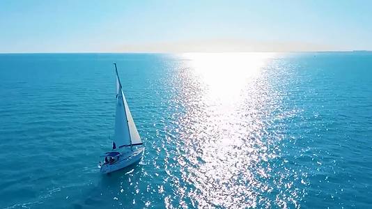 航拍风景海平线一艘帆船小船行驶在蔚蓝大海在水面划出波纹视频的预览图