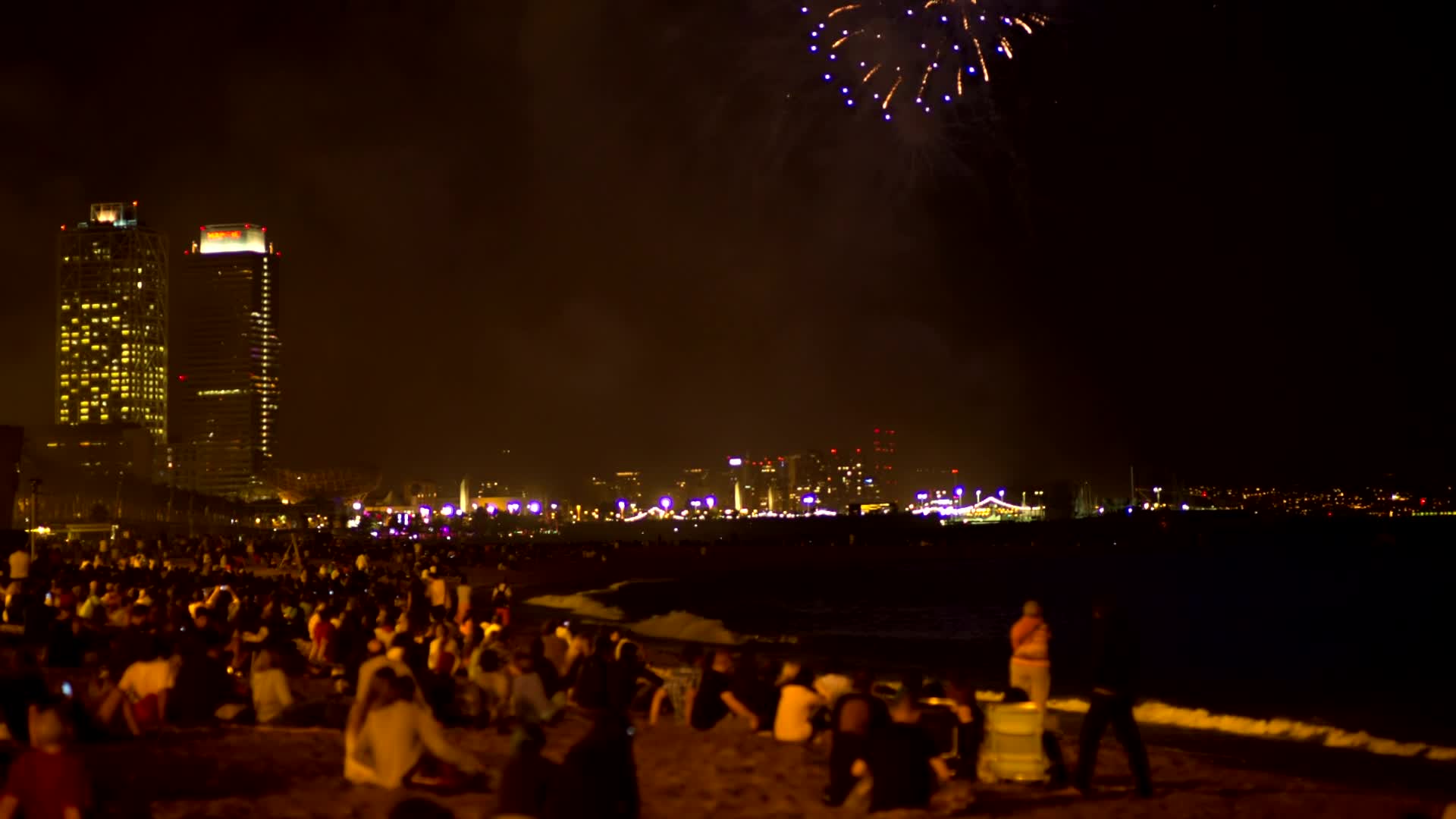 城市夜景人群在沙滩上看放烟花视频的预览图
