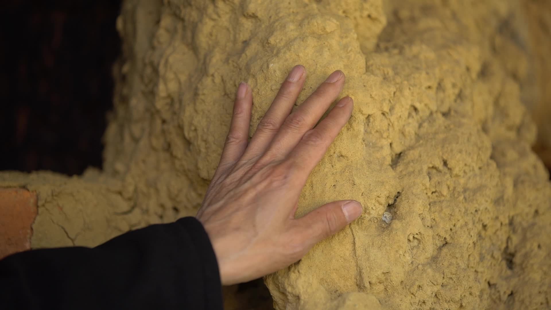 老人的手摩挲古老岩石视频的预览图