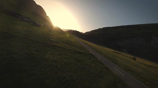 穿越机飞越草原公路傍晚夕阳山谷视频的预览图
