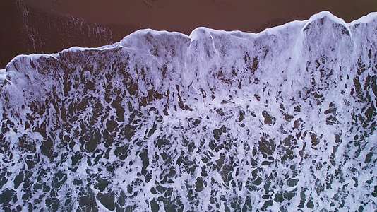 鸟瞰海面海浪撞击沙滩白色浪花视频的预览图