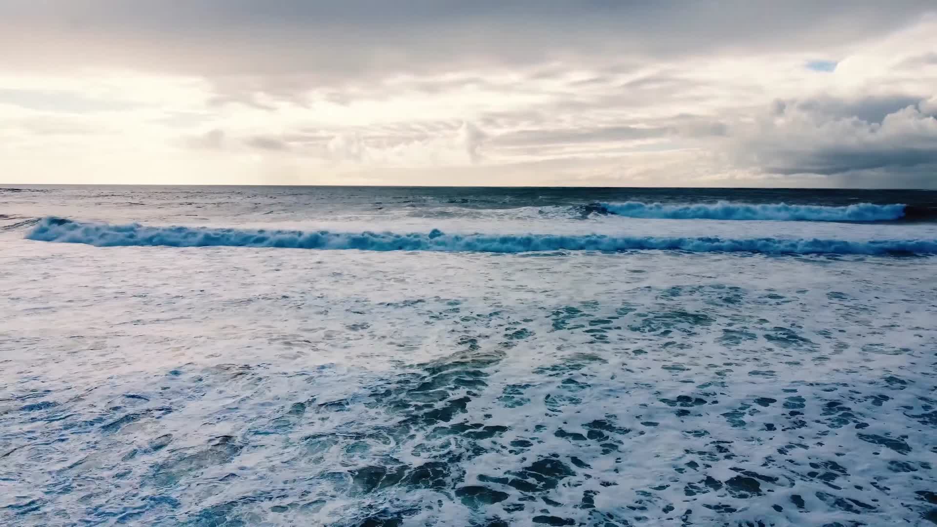 鸟瞰海面海浪撞击沙滩白色浪花视频的预览图