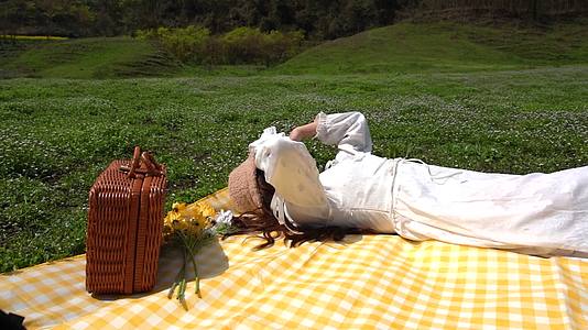 户外休闲少女野餐垫上晒太阳实拍视频视频的预览图