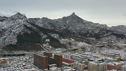 航拍雪后的山峰与城镇城区视频的预览图