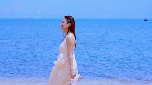 蔚蓝的大海边淡黄色的沙滩上甜甜微笑的美女视频的预览图