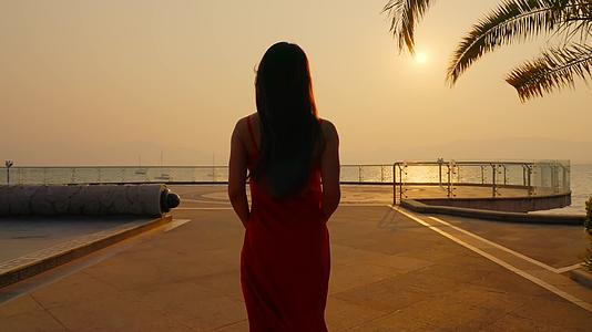 夕阳下晚霞里穿着红色裙子的美女背影剪影视频的预览图