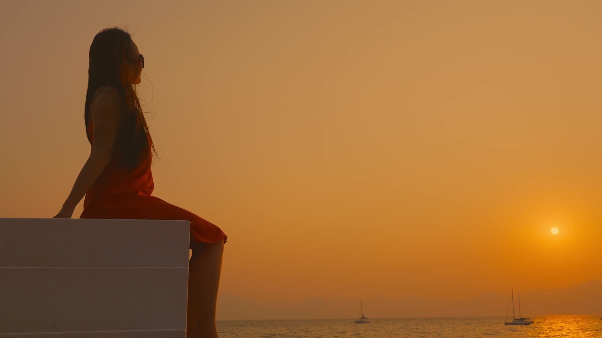 高台上夕阳下海边海风中看日落的女孩视频的预览图