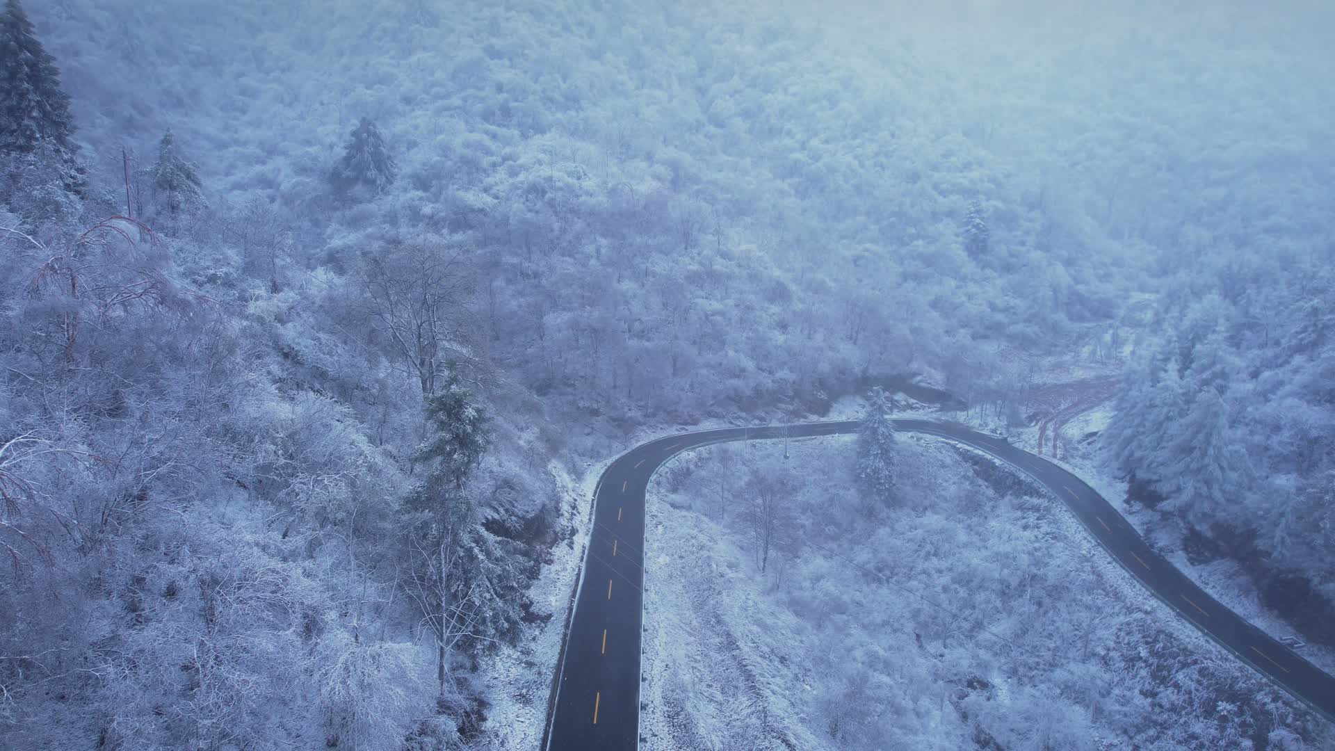 4K冬季下雪山上的道路航拍视频视频的预览图