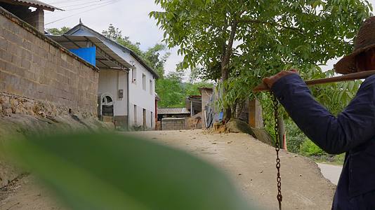 农村老人传统取水扁担水桶挑水背影特写视频的预览图