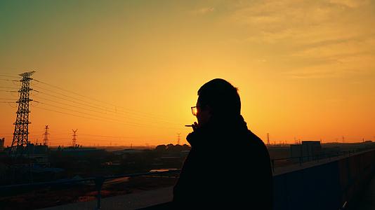 黄昏夕阳男人在天台抽烟落日剪影视频的预览图