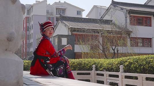坐在中国风建筑台阶上微笑的石林阿诗玛美女视频的预览图