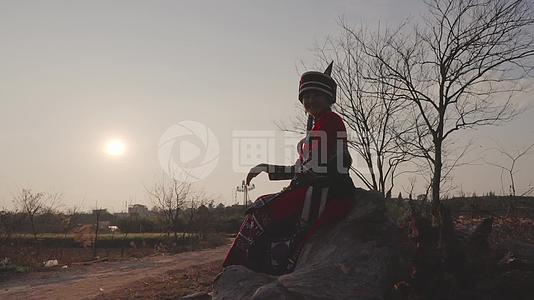 傍晚坐在枯树上看夕阳的石林阿诗玛彝族姑娘视频的预览图
